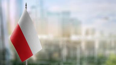 Kleine Flaggen der Polen auf einem abstrakten unscharfen Hintergrund