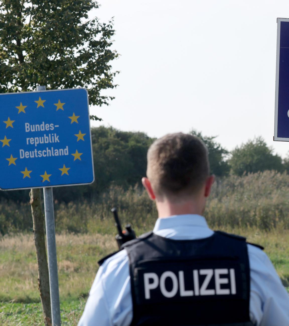 28.09.2023, Mecklenburg-Vorpommern, Linken: Bei einer flexiblen Schwerpunktkontrolle unmittelbar an der deutsch-polnischen Grenze in der Nähe des ehemaligen Grenzübergang Linken steht ein Bundespolizist vor den Schildern für Deutschland und Polen.
