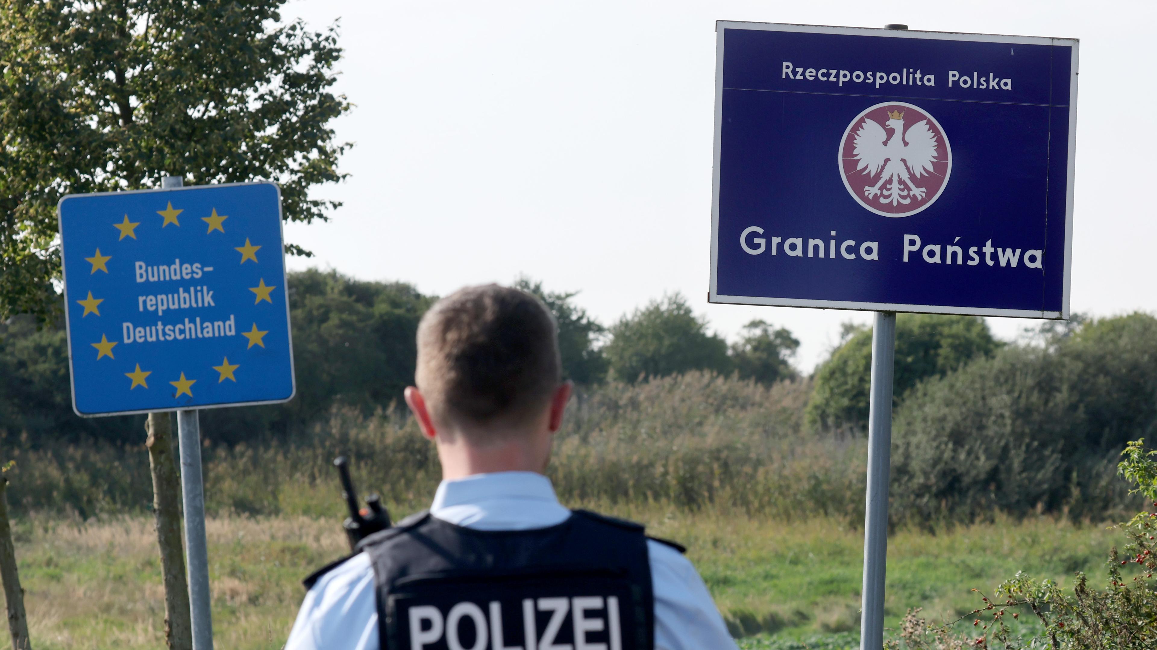 28.09.2023, Mecklenburg-Vorpommern, Linken: Bei einer flexiblen Schwerpunktkontrolle unmittelbar an der deutsch-polnischen Grenze in der Nähe des ehemaligen Grenzübergang Linken steht ein Bundespolizist vor den Schildern für Deutschland und Polen.