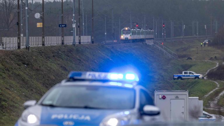 Ein Polizeiwagen ist sichtbar, welcher in der Nähe zu den Bahngleisen steht, auf denen ein Sprengstoff explodiert ist.
