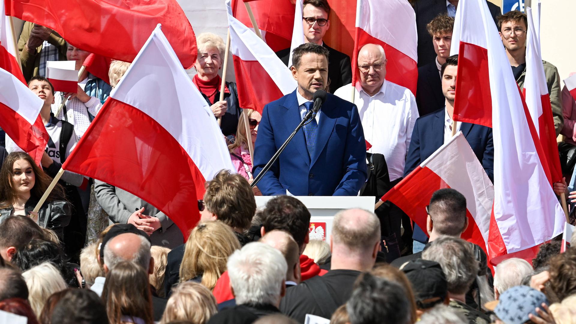 Rafal Trzaskowski hält im Wahlkampf für die Präsidentschaftswahlen in Polen eine Rede. Um ihn herum sind Menschen versammelt, die polnische Flaggen halten.