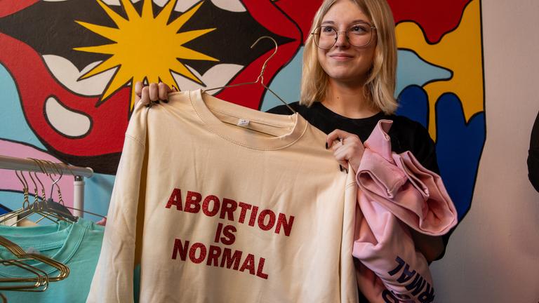 Polen, Warschau: Eine Frau hält einen Kapuzenpullover hoch, auf dem in fetten Buchstaben der Satz „Abtreibung ist normal“ aufgedruckt ist.