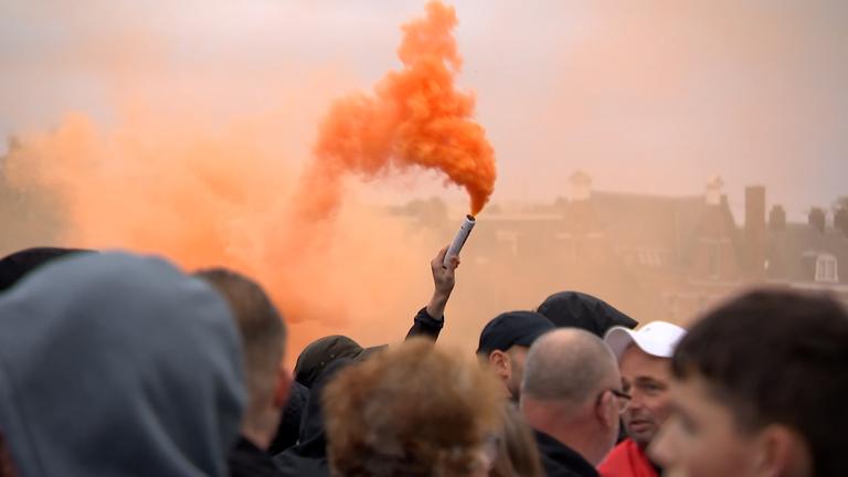 Ein Demonstrant des rechtsextremen Protests in den Niederlanden hält eine Rauchfackel, aus der orangeroter Rauch aufsteigt.