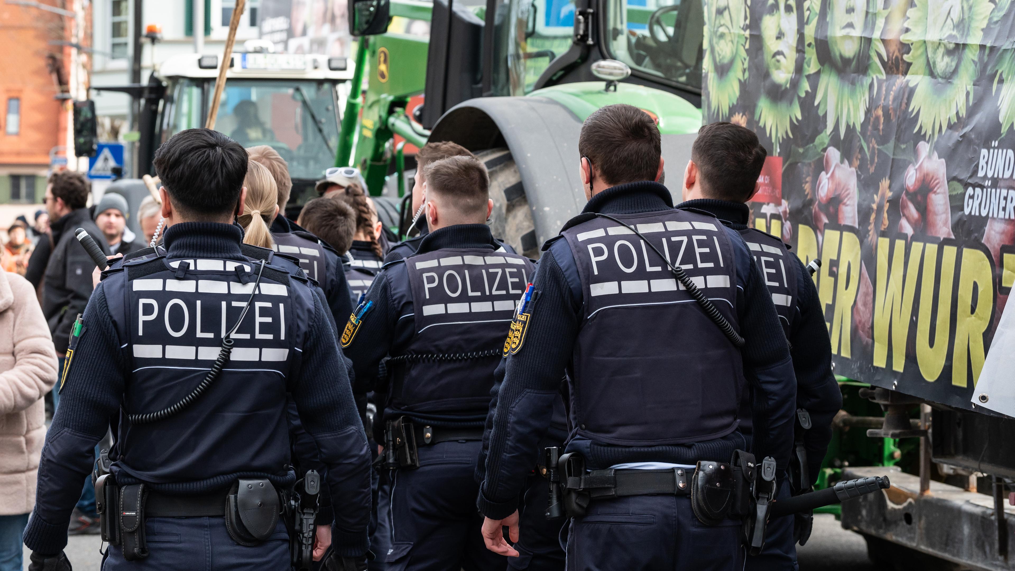 Baden-Württemberg, Biberach an der Riß: Polizisten gehen während einer Demonstration vor Beginn des politischen Aschermittwochs der baden-württembergischen Grünen vor der Stadthalle in Biberach an der Riß.