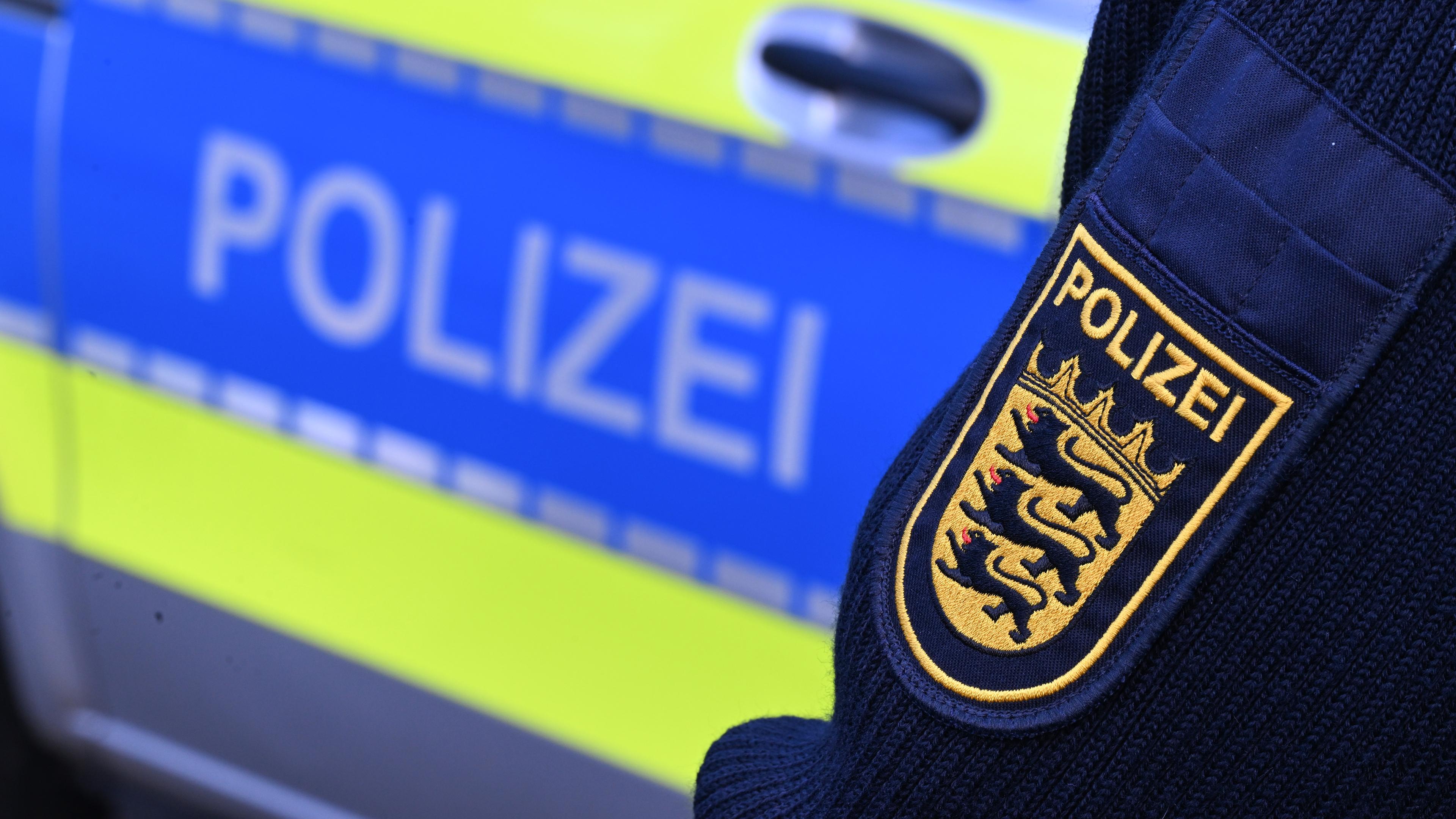 Wappen der Polizei auf Uniform eines Polizisten vor seinem Polizeiwagen.