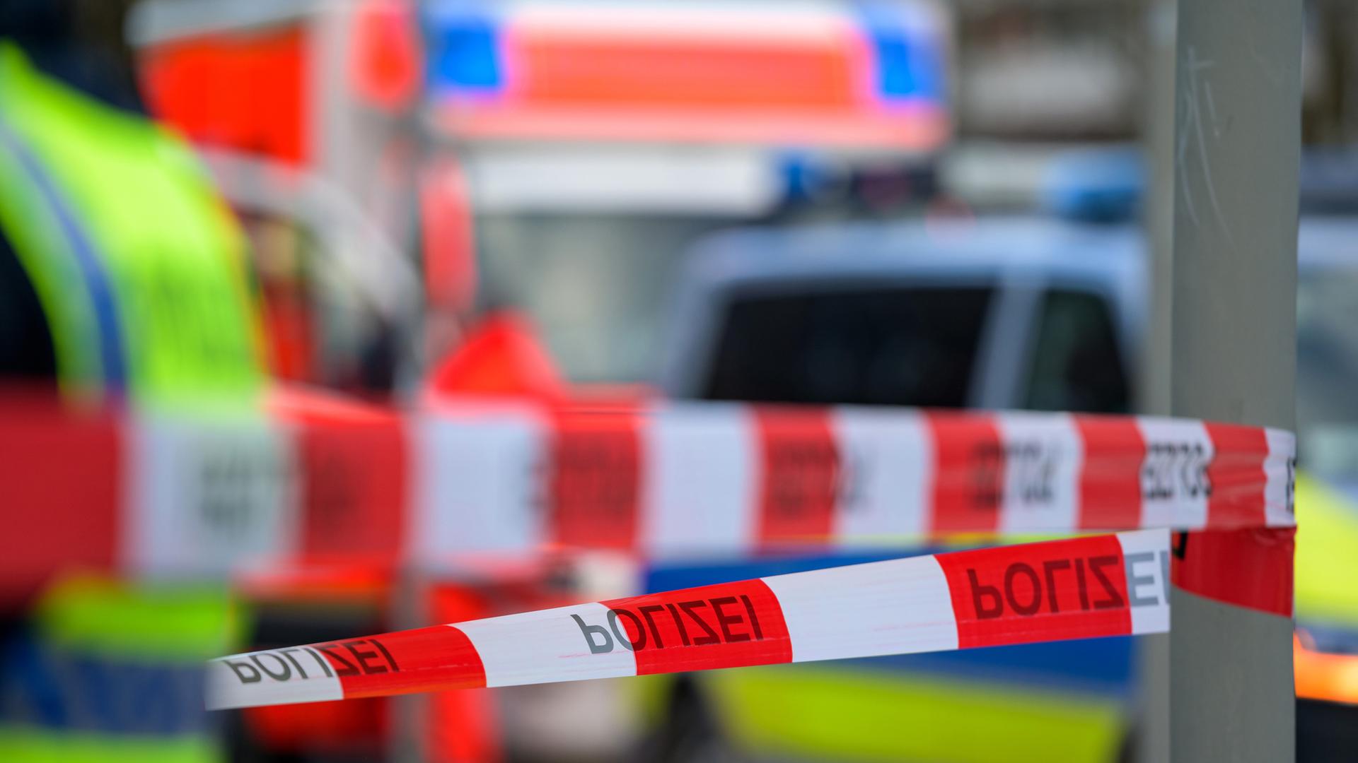 insatzfahrzeuge von Feuerwehr und Polizei stehen hinter dem mit Flatterband abgesperrten Einsatzort