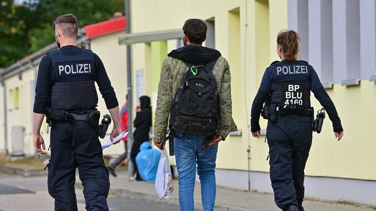 Zwei Beamte der Bundespolizei begleiten einen Flüchtling
