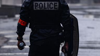 Während Schülerprotesten in Lyon, Frankreich, hält ein französischer Polizist eine Tränengasgranate in der Hand.