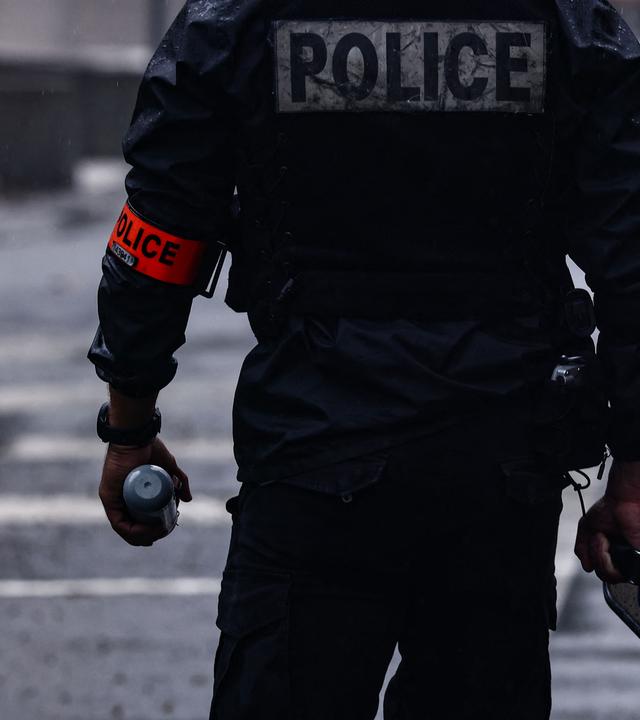 Während Schülerprotesten in Lyon, Frankreich, hält ein französischer Polizist eine Tränengasgranate in der Hand.