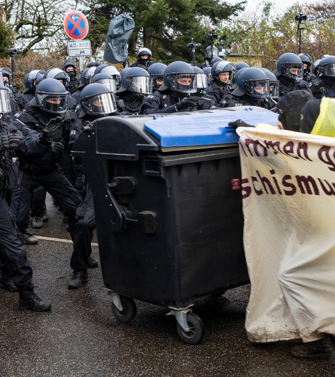 Demonstranten schieben am 29.11.2025 während der Demonstrationen gegen den AfD-Parteitag Mülltonnen in Richtung der Polizei. 
