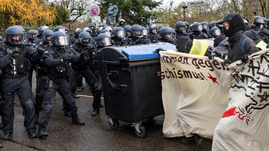 Demonstranten schieben am 29.11.2025 während der Demonstrationen gegen den AfD-Parteitag Mülltonnen in Richtung der Polizei. 