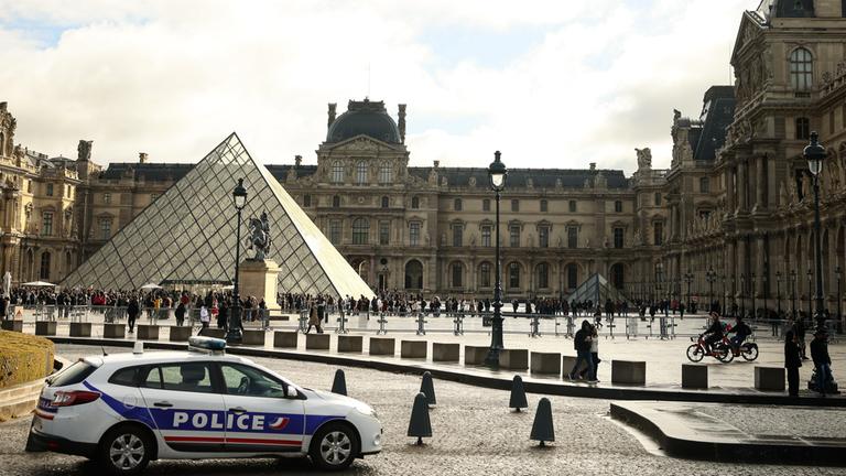 Ein Polizeiwagen steht vor dem Louvre