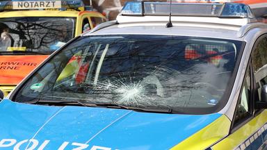 Herne: Ein Polizeifahrzeug steht mit einer zerstörten Windschutzscheibe an einem tatort. Die Polizei hat in Herne einen mutmaßlichen Messerangreifer erschossen.