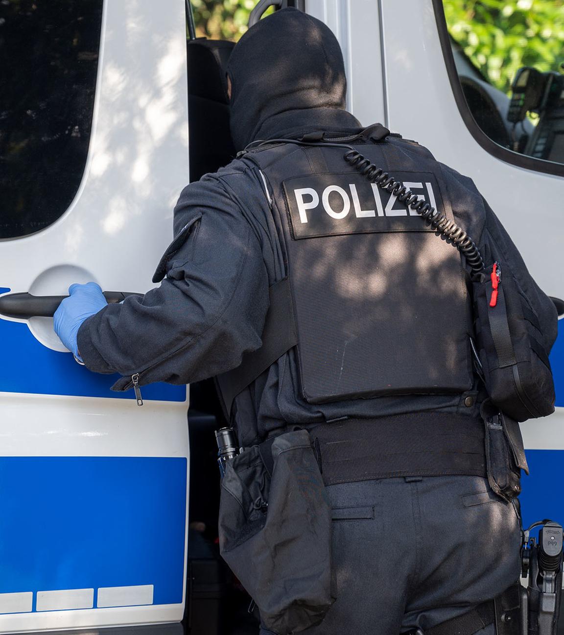 Archiv: Ein Polizist steht an einem Polizeifahrzeug in Nordrhein-Westfalen