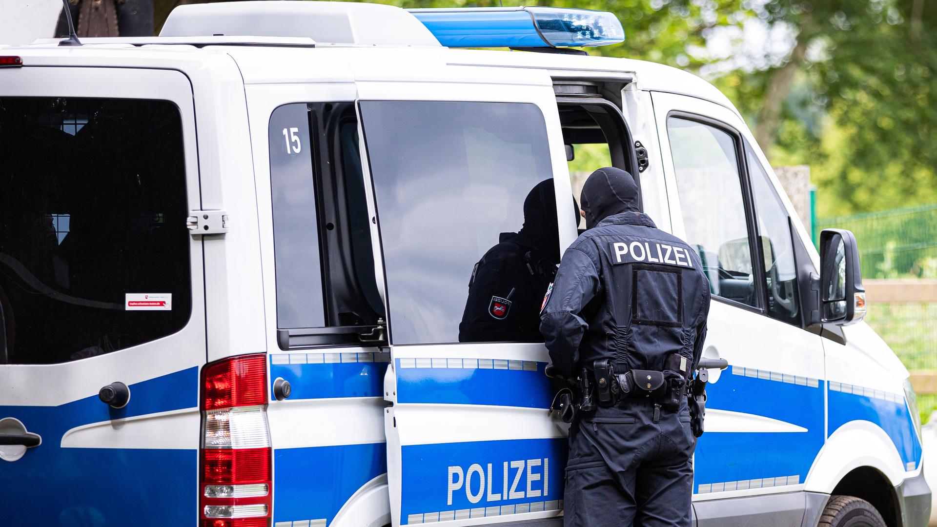 Ein Polizist steht an einem Einsatzfahrzeug (Archivfoto)