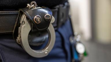 Symbolbild:  Eine Handschelle hängt am Gürtel eines Polizisten der Polizeiinspektion 