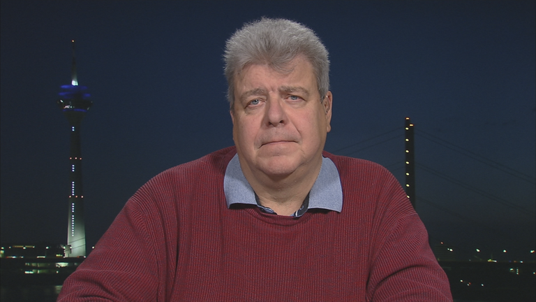 ZDF-Reporter Thomas Münten vor einer Grafik der Skyline von Düsseldorf.