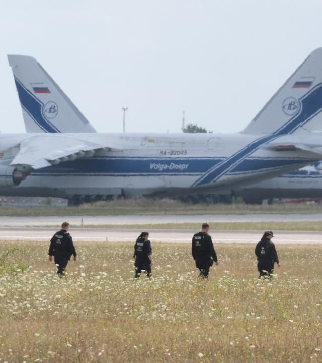 Polizisten gehen über eine Wiese auf dem Gelände des Flughafen-Leipzig. 