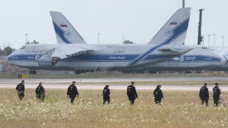 Polizisten gehen über eine Wiese auf dem Gelände des Flughafen-Leipzig. 