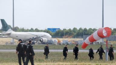 Polizisten gehen über eine Wiese auf dem Gelände des Flughafen-Leipzig am 07.08.2026.