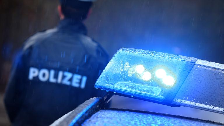Polizist steht neben Polizeiwagen mit Blaulicht