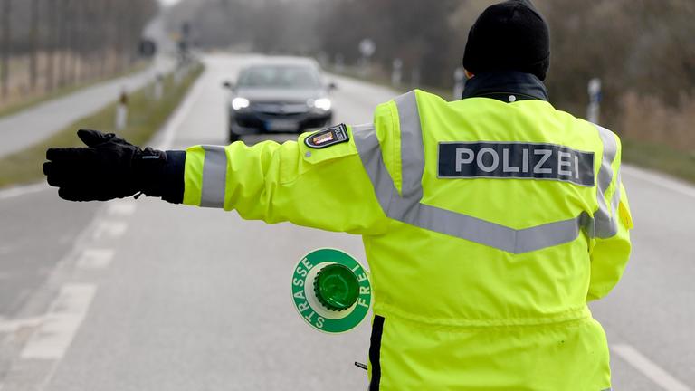Ein Polizist winkt einen Autofahrer zu einer Kontrollstelle