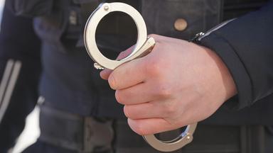 Polizist hält Handschellen in der Hand