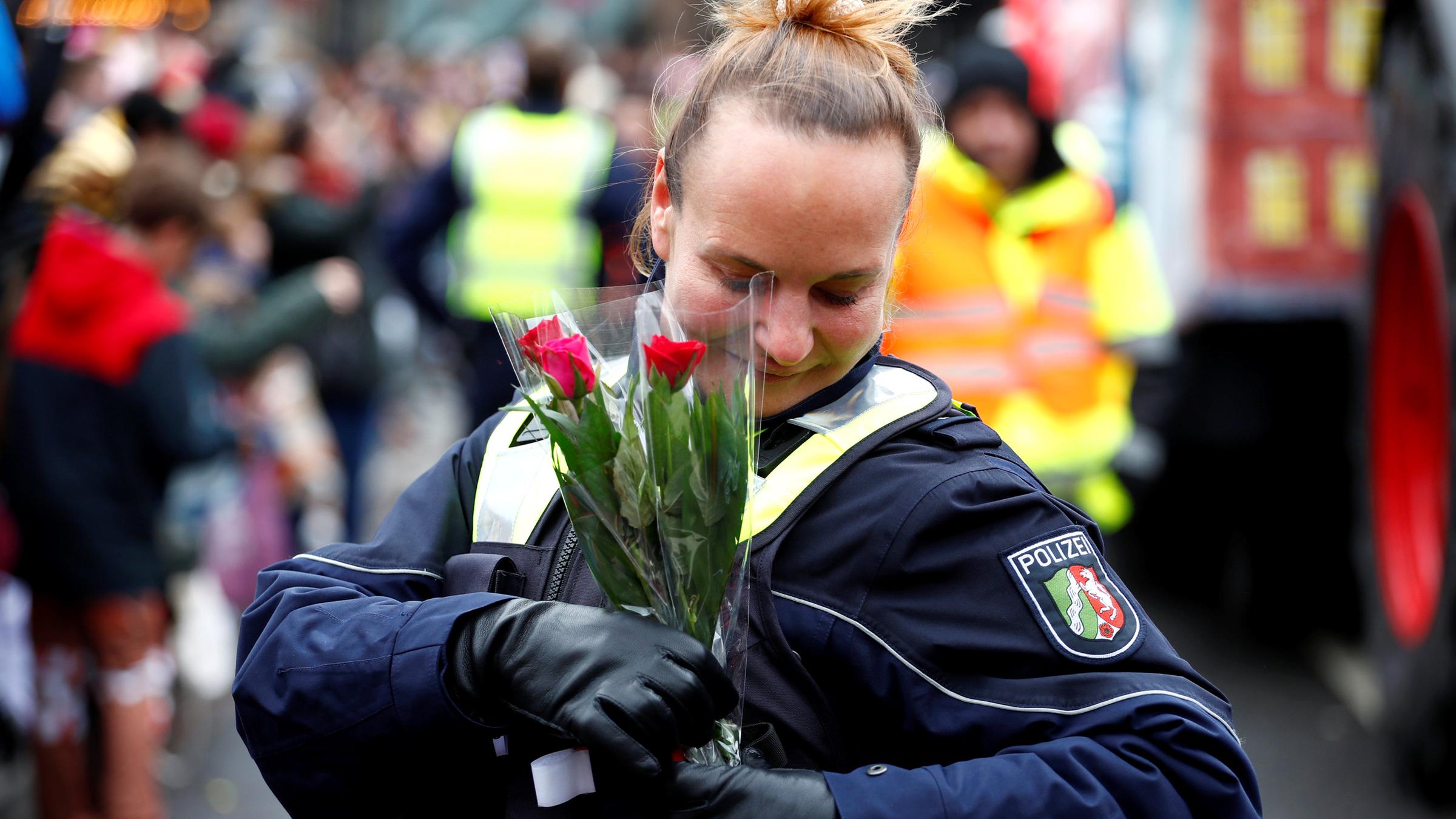Eine Polizistin steckt sich am Düsseldorfer Rosenmontagszug ein paar Blumen in die Jacke