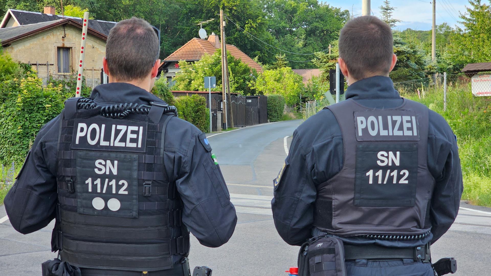 Sachsen, Mahlitzsch: Zwei Polzisten stehen auf einer Straße.