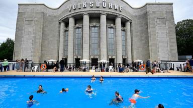 Besucher schwimmen am 07.08.2026, dem Tag der Eröffnung, im sogenannten „Volksbad“, das vor der Volksbühne am Rosa-Luxemburg-Platz in Berlin eingerichtet wurde. 