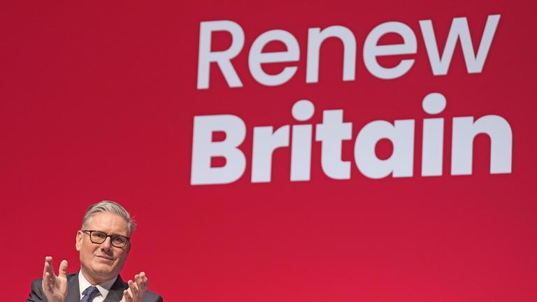Der britische Premierminister und Parteivorsitzende von Labour, Keir Starmer, steht auf dem Labour-Parteitag vor der Aufschrift "Renew Britain".
