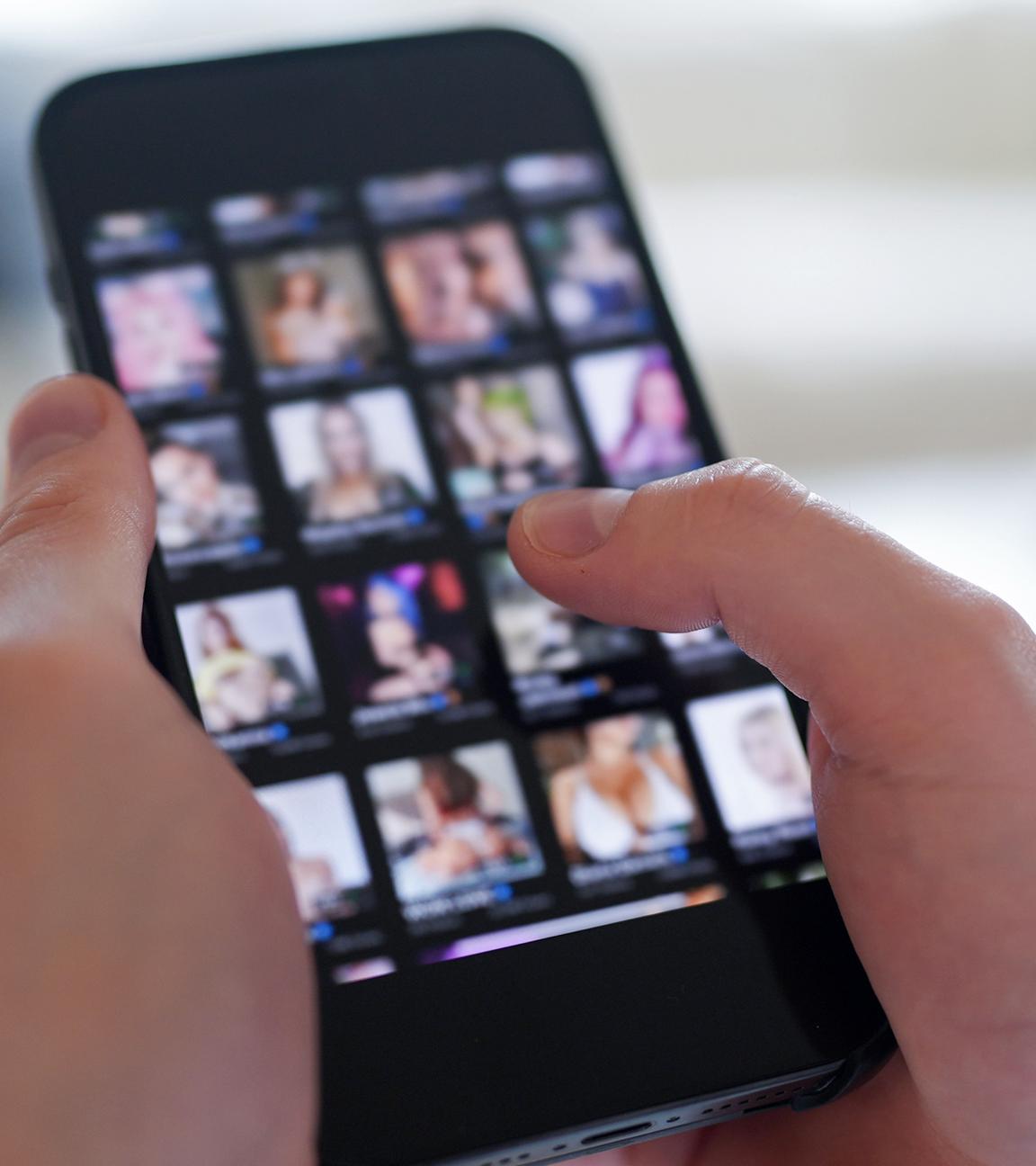 Ein junger Mann schaut sich auf einem Smartphone eine Porno-Internetseite an