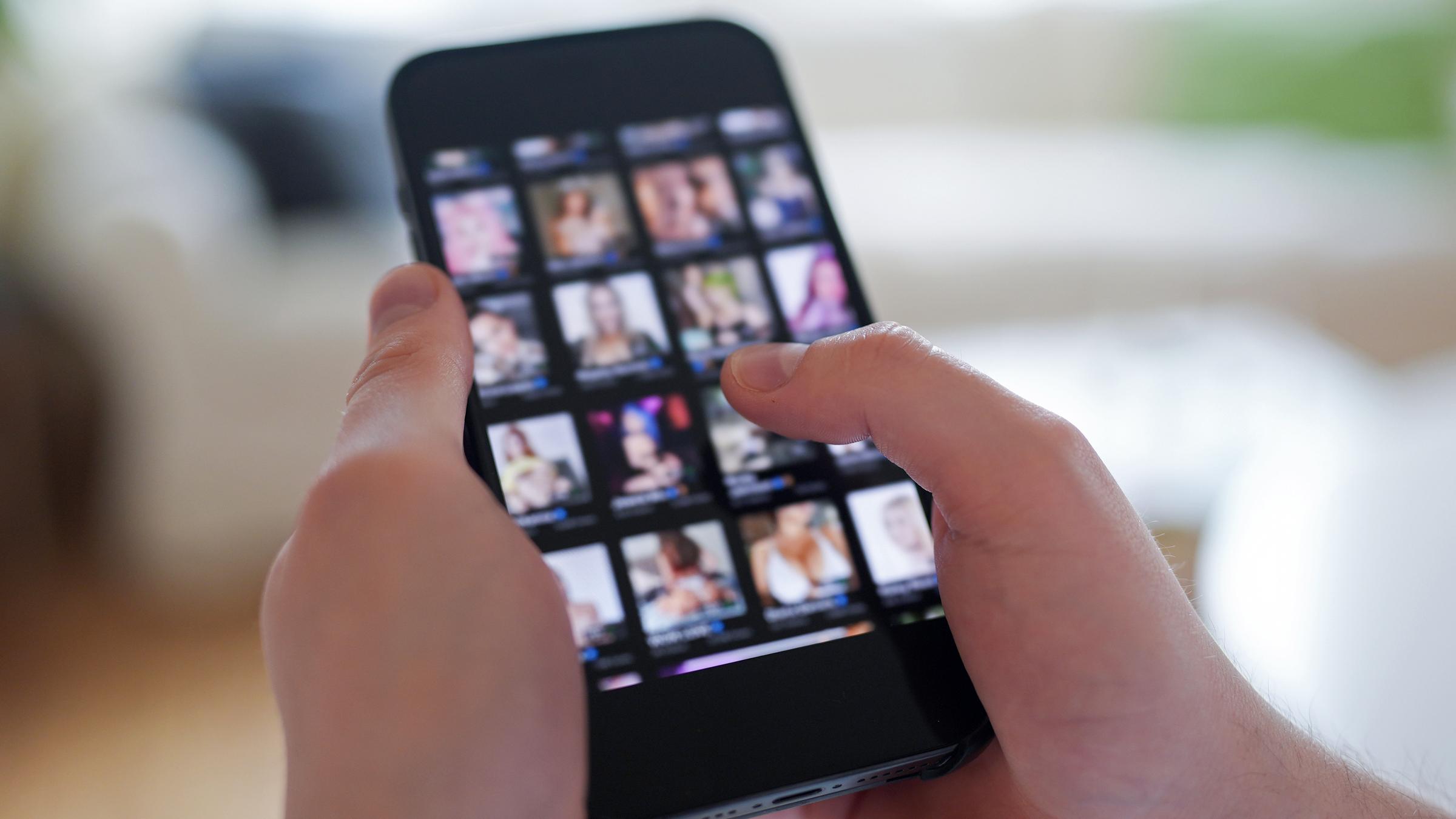 Ein junger Mann schaut sich auf einem Smartphone eine Porno-Internetseite an