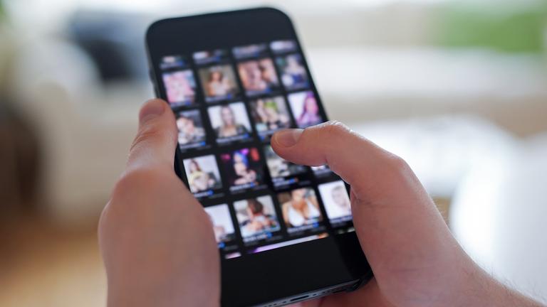 Ein junger Mann schaut sich auf einem Smartphone eine Porno-Internetseite an