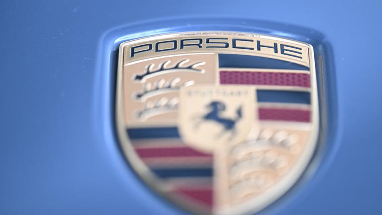 10.10.2025, Baden-Württemberg, Stuttgart: Das Logo des Stuttgarter Sportwagenbauers Porsche an einem Sportwagen der Marke.