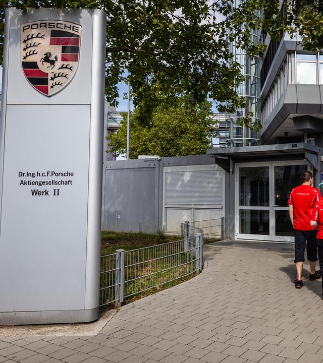 Mitarbeiter von Porsche gehen zu einem Gebäude am Firmensitz in Stuttgart-Zuffenhausen.