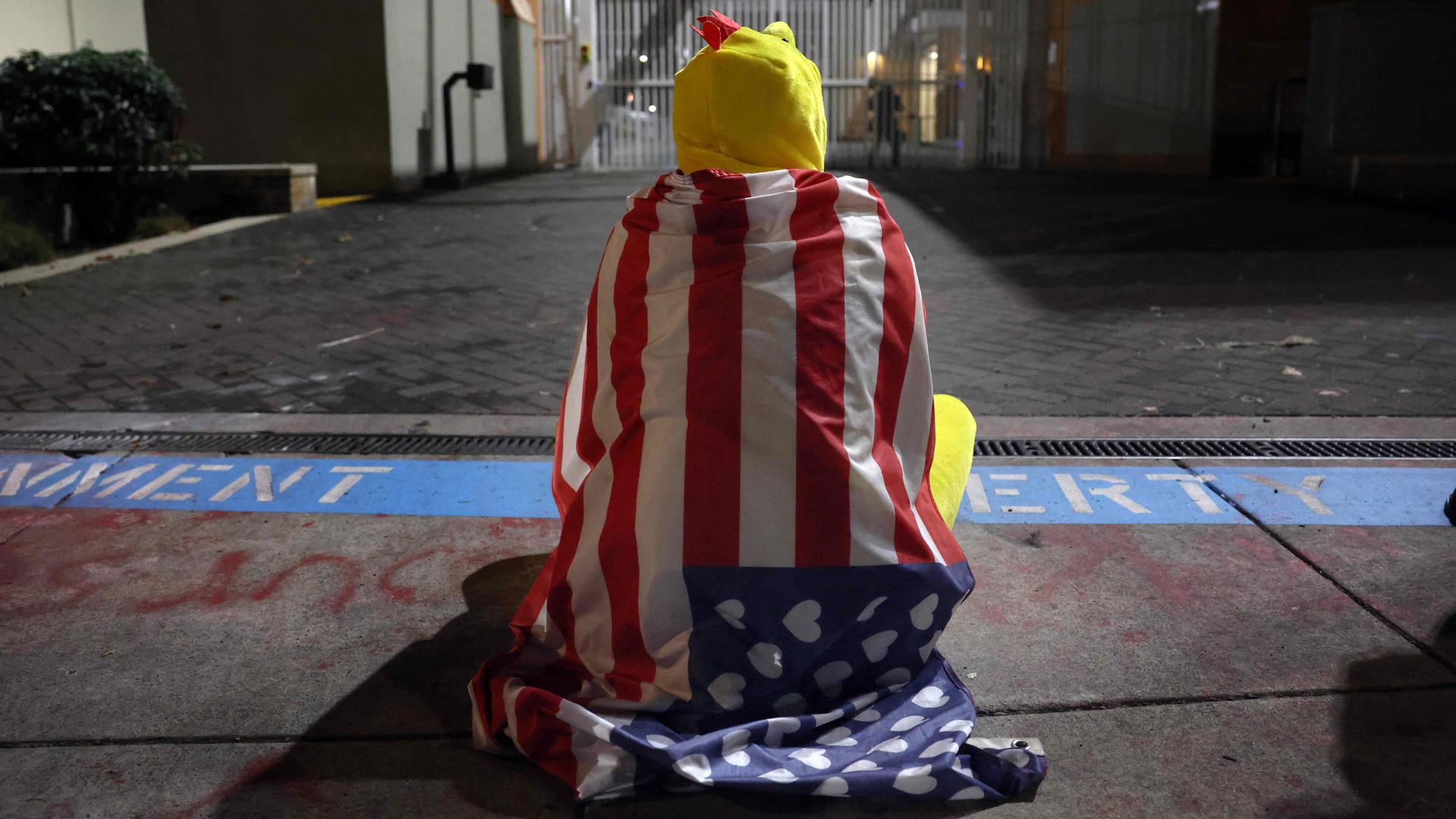 Ein Mann in einem Hühnerkostum sitzt vor einem Gebäude der US-Einwanderungsbehörde in Portland.