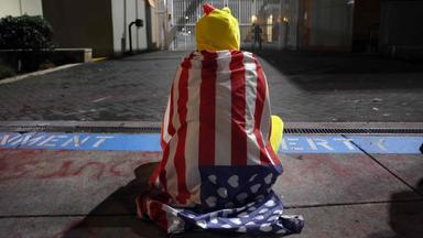 Ein Mann in einem Hühnerkostum sitzt vor einem Gebäude der US-Einwanderungsbehörde in Portland.