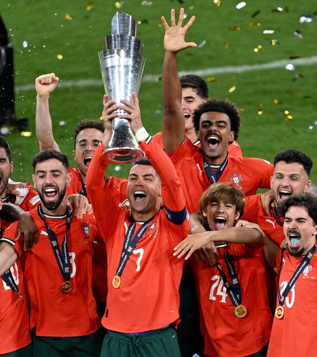 Portugals Cristiano Ronaldo (M) jubelt mit der Trophäe über den Sieg der Nations League.