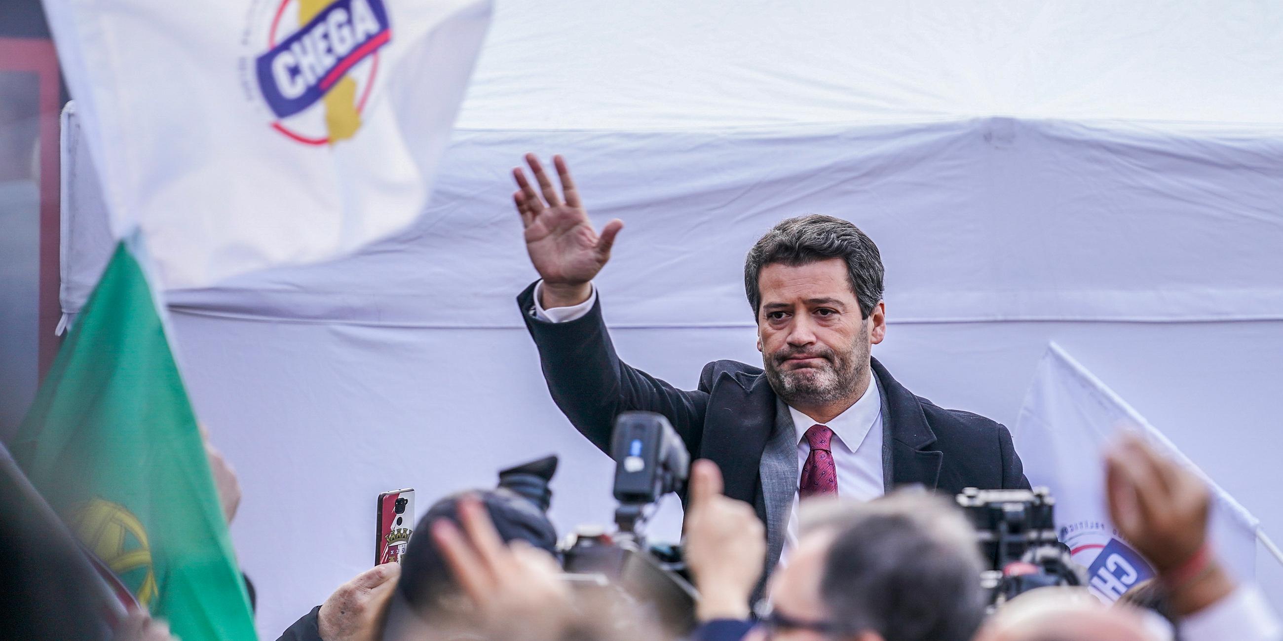 Chega Parteivorsitzender André Ventura spricht vor einem großen Publikum, links neben ihm ist die Flagge der Partei zu sehen.