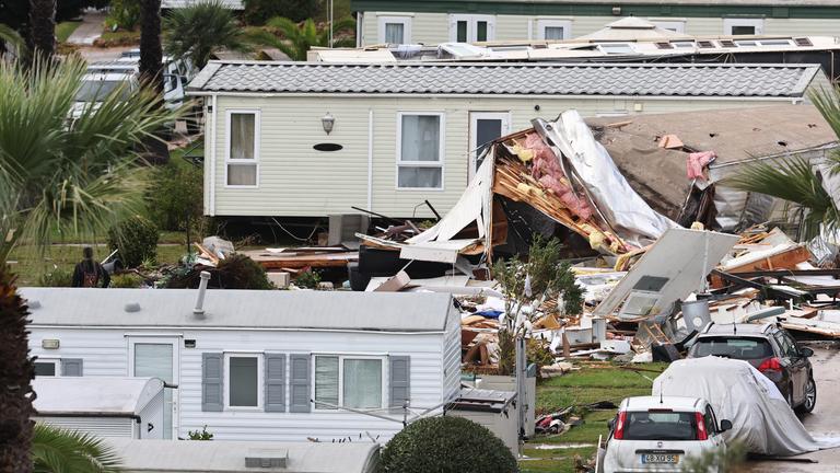 Ein verwüsteter Campingplatz mit kleinen Häuschen, eins scheint sehr zerstört.