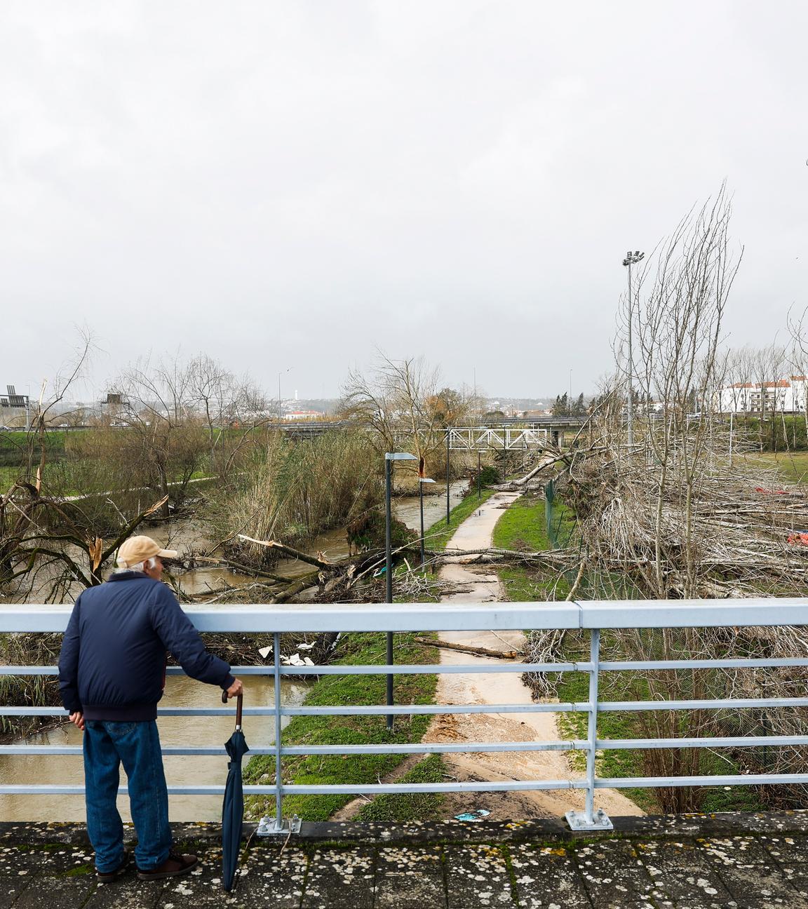 Ein Mann schaut von einer Brücke auf die Unwetter-Folgen in Portugal