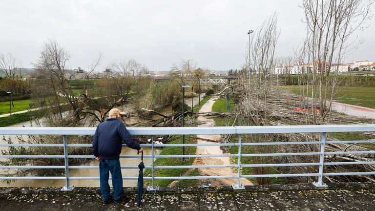 Ein Mann schaut von einer Brücke auf die Unwetter-Folgen in Portugal