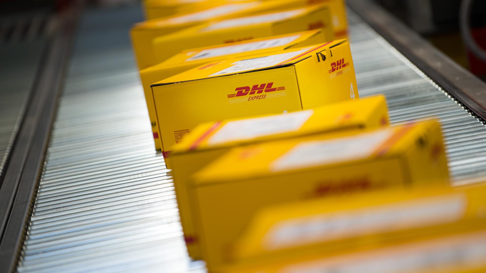 Zahlreiche Pakete von DHL laufen über ein Förderband der Deutschen Post