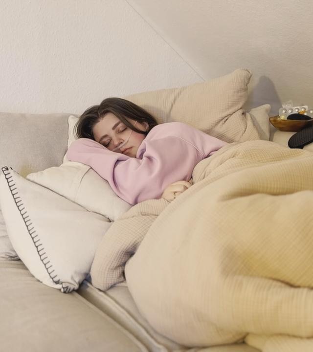 Frau liegt im Bett. Sie leidet am "Post-Vac-Syndrom"