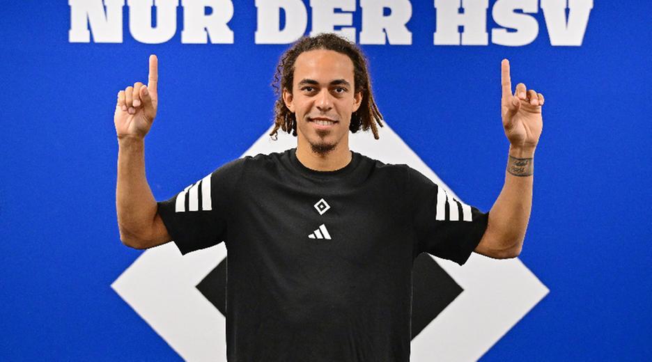 Yussuf Poulsen posiert vor dem HSV-Logo