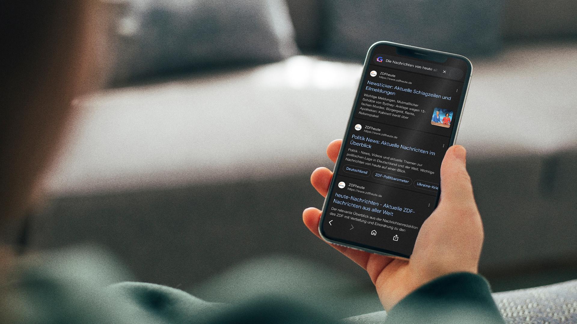 Eine Person hält ein Smartphone in der Hand. Darauf ist die ZDFheute bei Google zu sehen. Symbolbild.