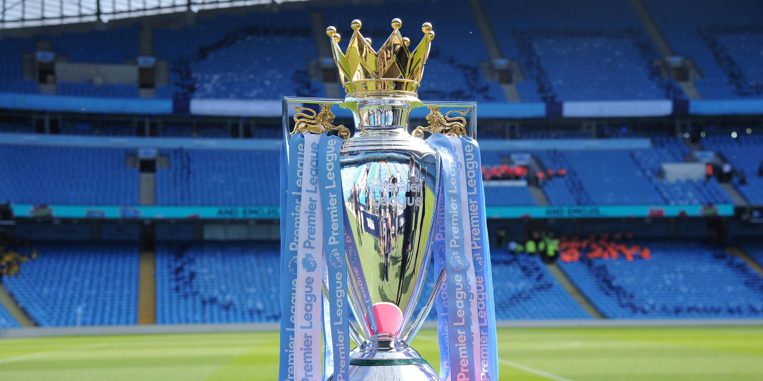 Der Sigerpokal der englischen Liga Premier League von 2018 steht auf einem Podest vor einem leeren Stadion.