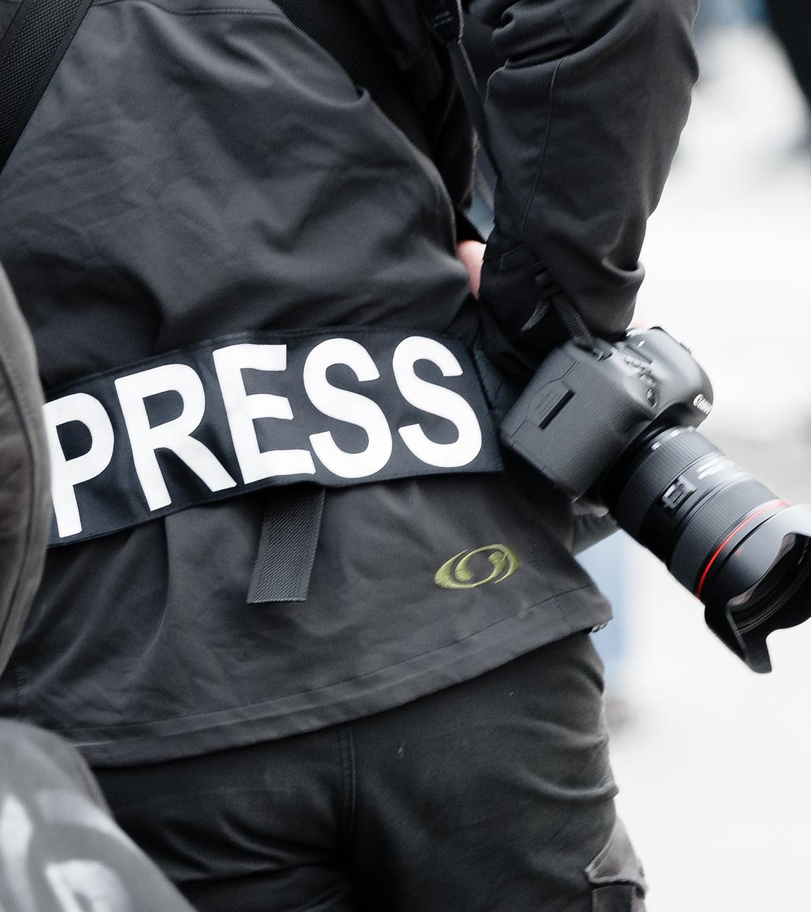 Ein Fotoreporter trägt auf einer Demonstration einen Aufnäher mit dem Text «PRESS» auf seiner Jacke, um sich gegenüber Polizei und Demonstranten als Journalist zu kennzeichnen