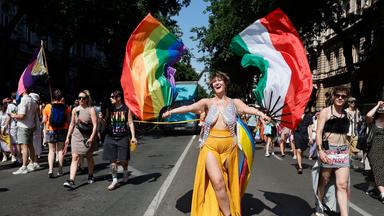 Teilnehmer marschieren während der 31. Budapest-Pride-Veranstaltung in der Innenstadt von Budapest, Ungarn. Eine Frau schwingt eine ungarische und eine Pride-Flagge.